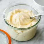 fresh mayo in a glass container with a spoon dipped it in