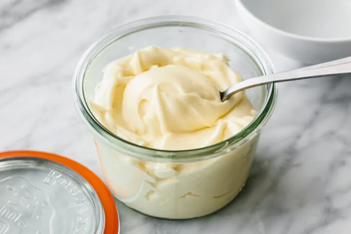 fresh mayo in a glass container with a spoon dipped it in